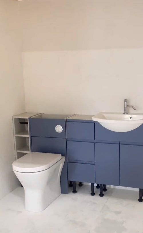 Bathroom training bay with a toilet, blue vanity units and basin at The Plumbing School
